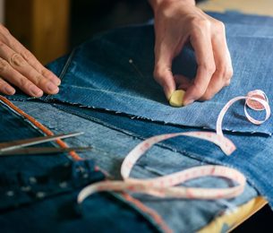 Rose N Silk performing alterations on a pair of jeans, using a sewing machine and various tools