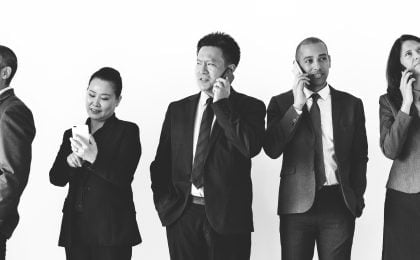 Two women and three men talking on the phone while wearing perfectly fitted suits, emphasizing the importance of suit alterations in creating a professional and polished appearance."